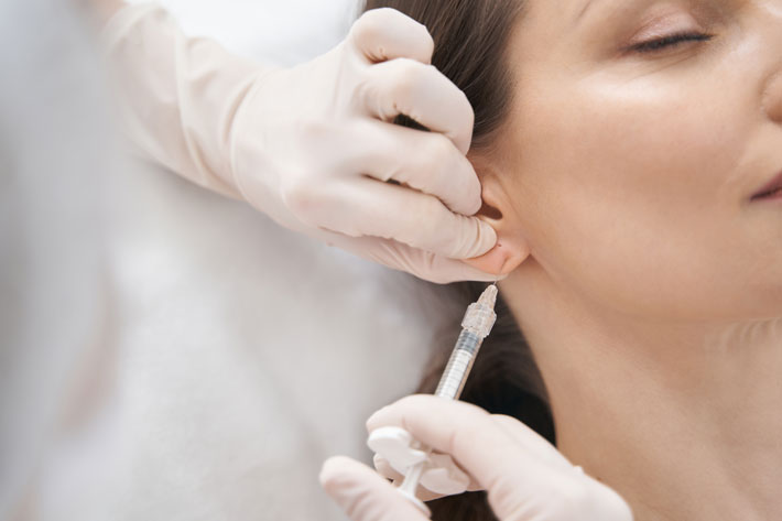 Close up of female patient receiving rejuvenation earlobe injection in cosmetology clinic