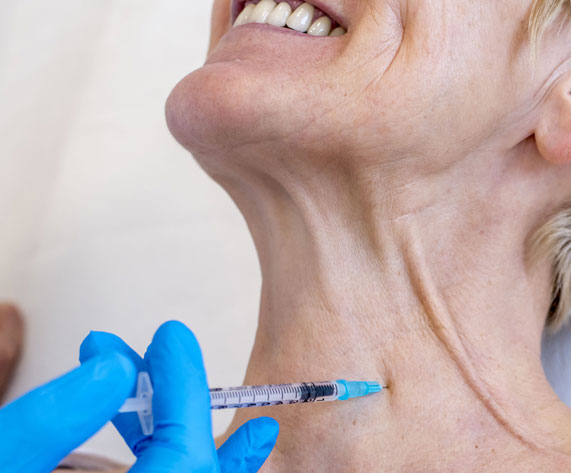 A vertical shot of a cheerful old female getting neck botox in a hospital